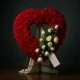 Funeral heart of red carnations with a spray of white roses