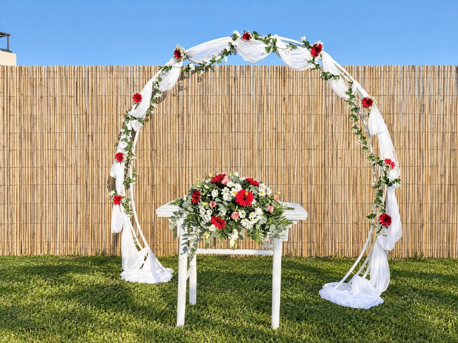 Round arch with tulle and red and white roses in a garden
