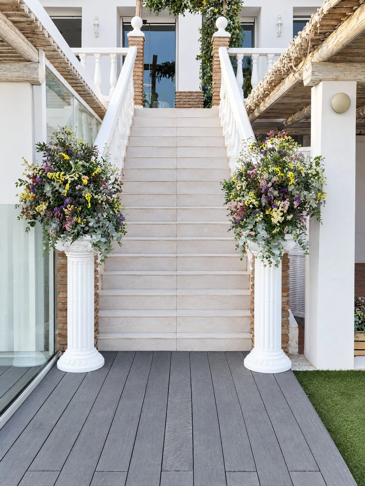 Two white columns with flowers at the foot of a staircase
