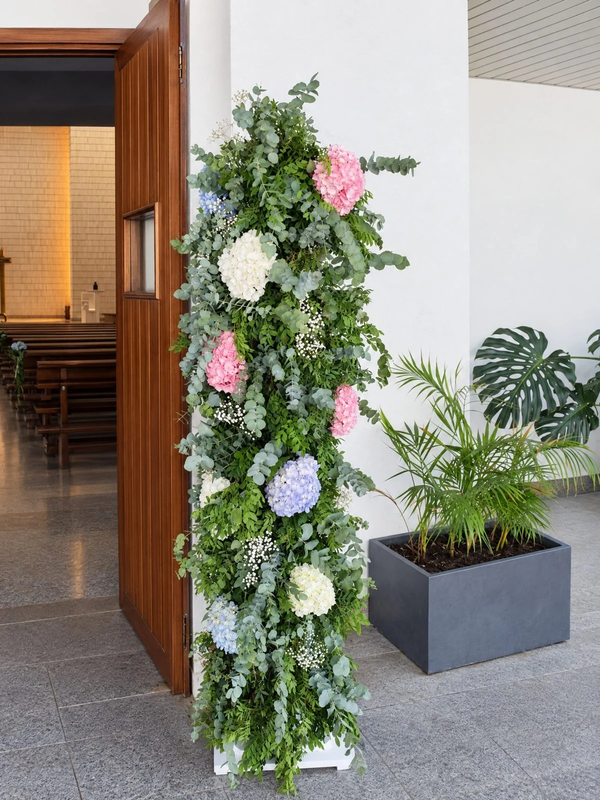 Wedding flowers at the church door: a column of pink, white and blue hydrangeas with eucalyptus