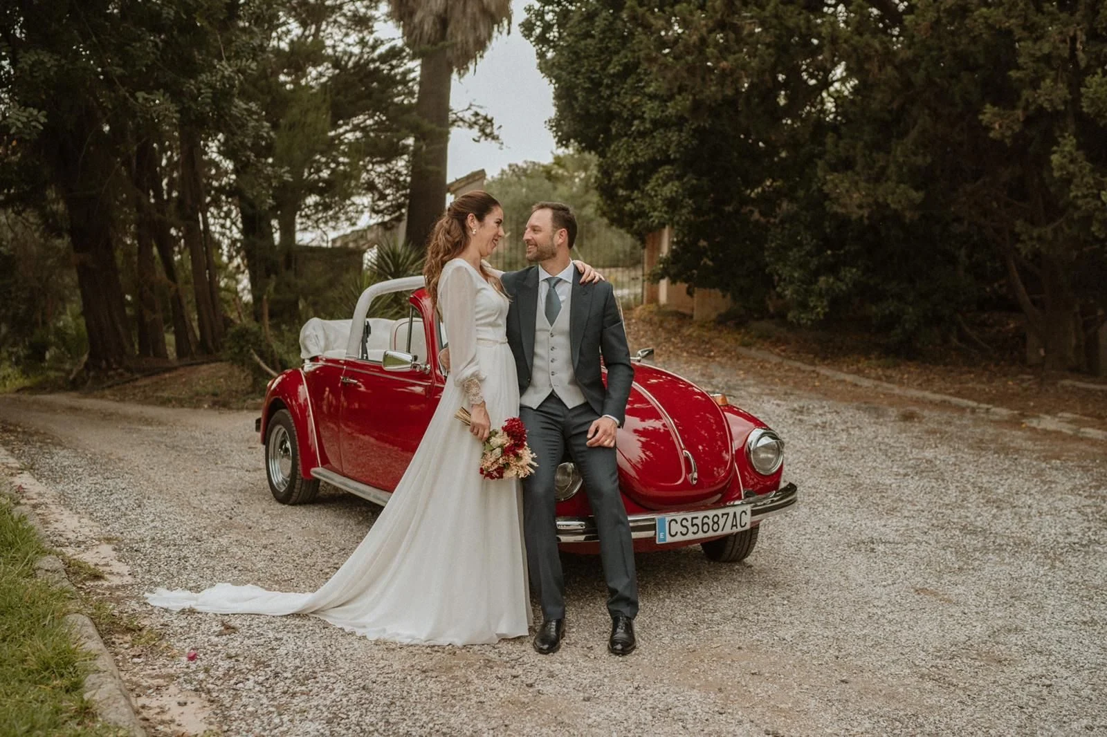 Bride and groom beside a red classic car, with the Florymar bouquet