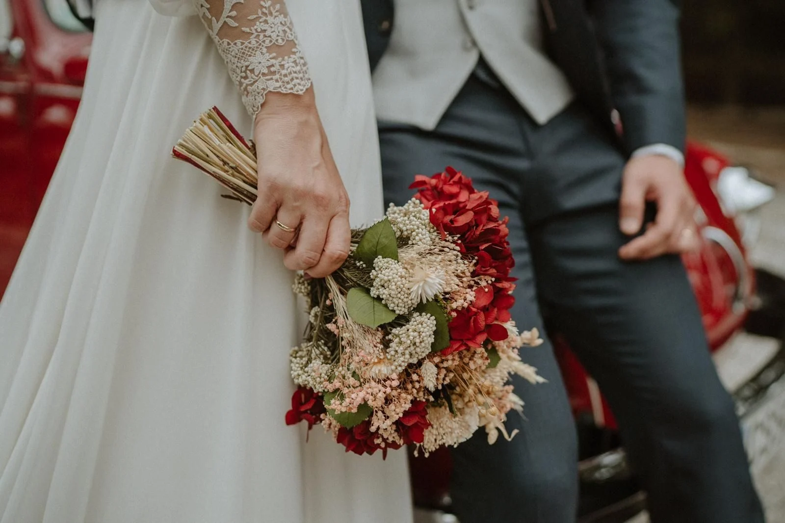 Red and cream bridal bouquet in the couple's hands